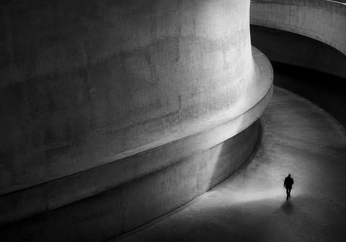 Curved concrete wall with a small figure walking below